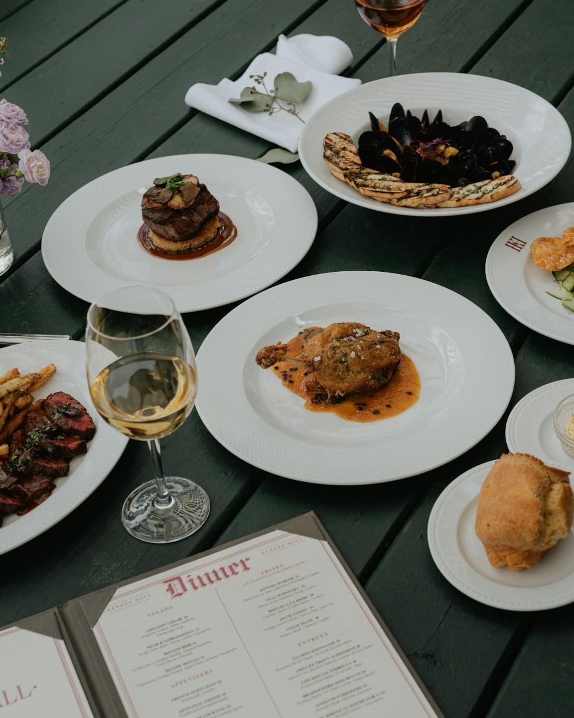 Gourmet outdoor dining spread on a slatted table.