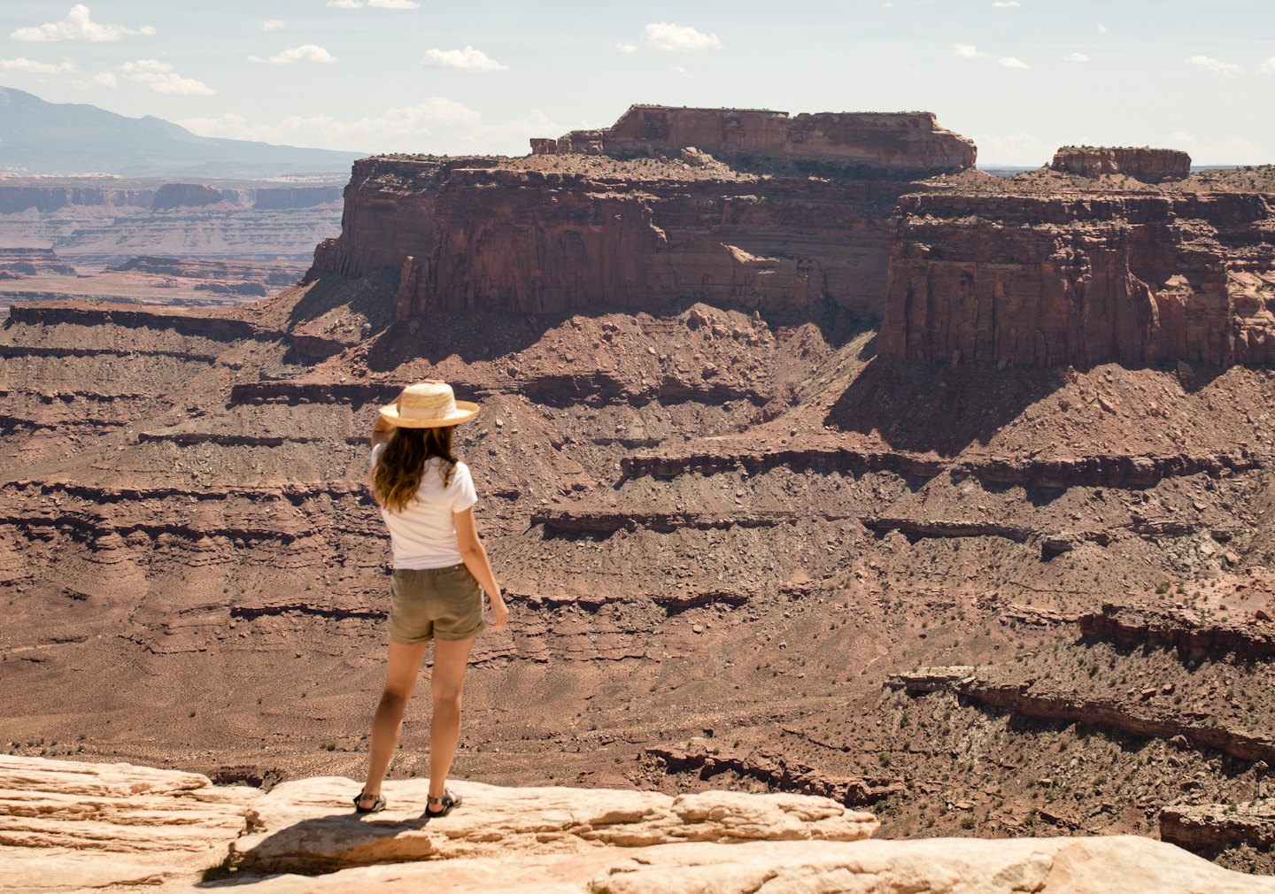 Traveler stands on a rocky outcrop overlooking a vast canyon.
