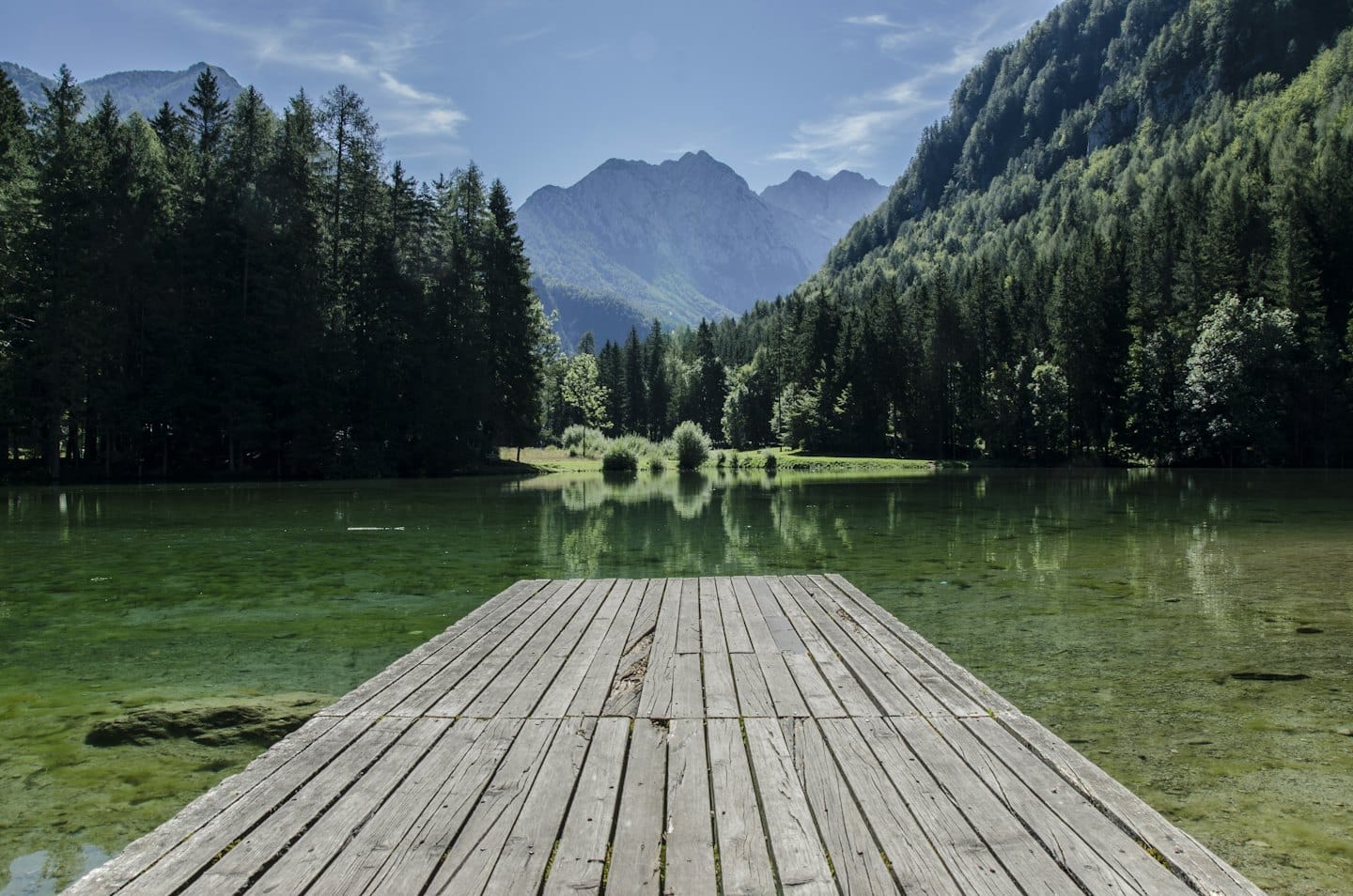 A long wooden pier extends into a clear mountain lake.