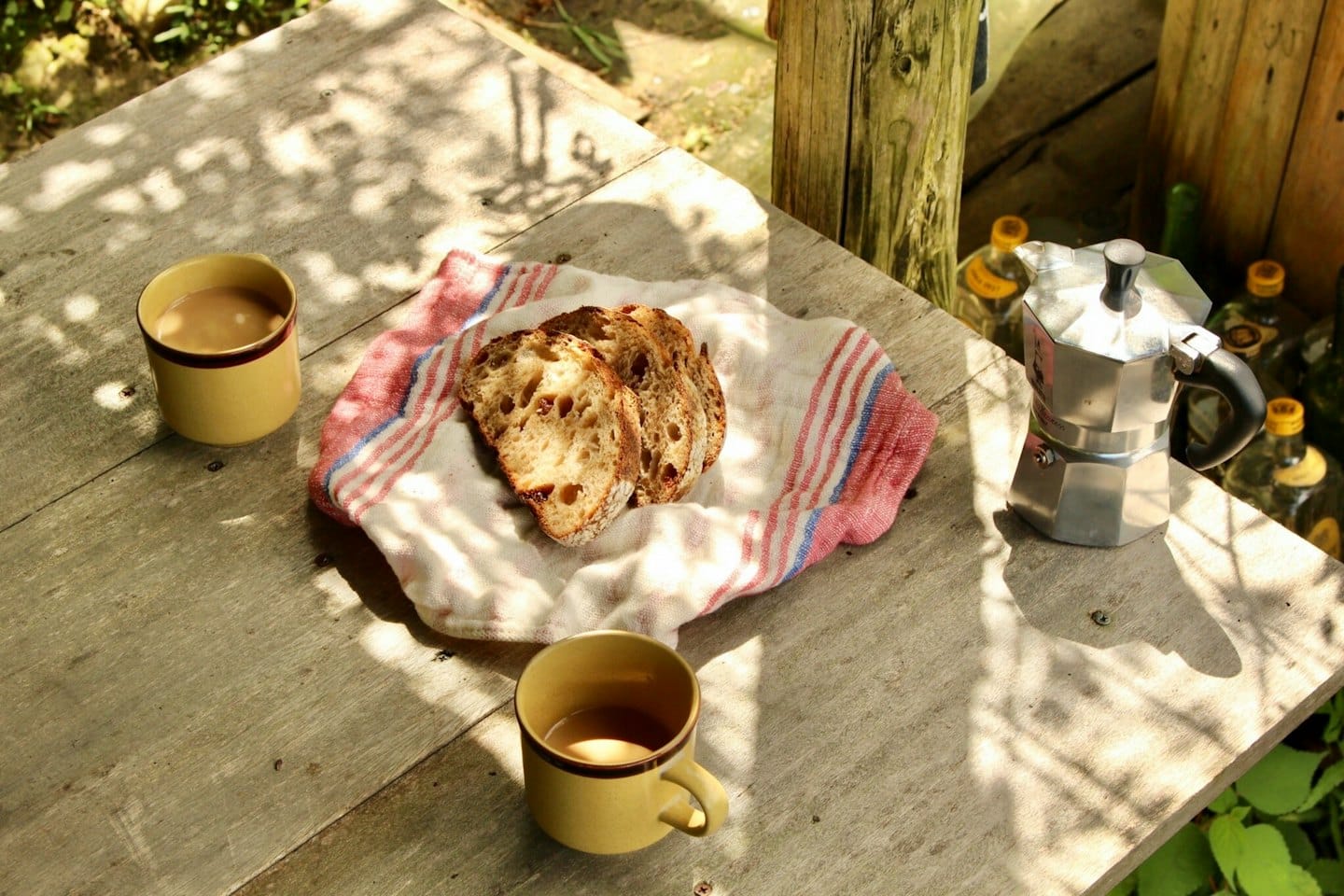 Coffee mugs and bread slices sit on a wooden table.